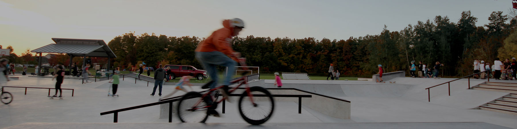 young boy on BMX bike performing skill tricks at a local skate park